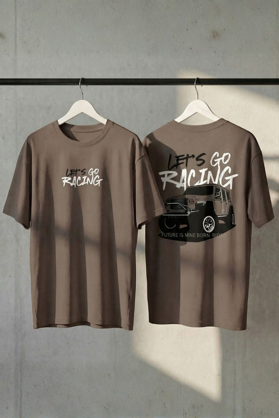 Chocolate t-shirt with 'Let's Go Racing' text on a hanger against a gray wall.