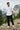 Man standing on a mountain path with trees and clouds in the background