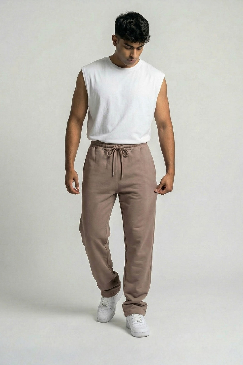 Man wearing a white sleeveless shirt and Chocolate jogger on a plain background