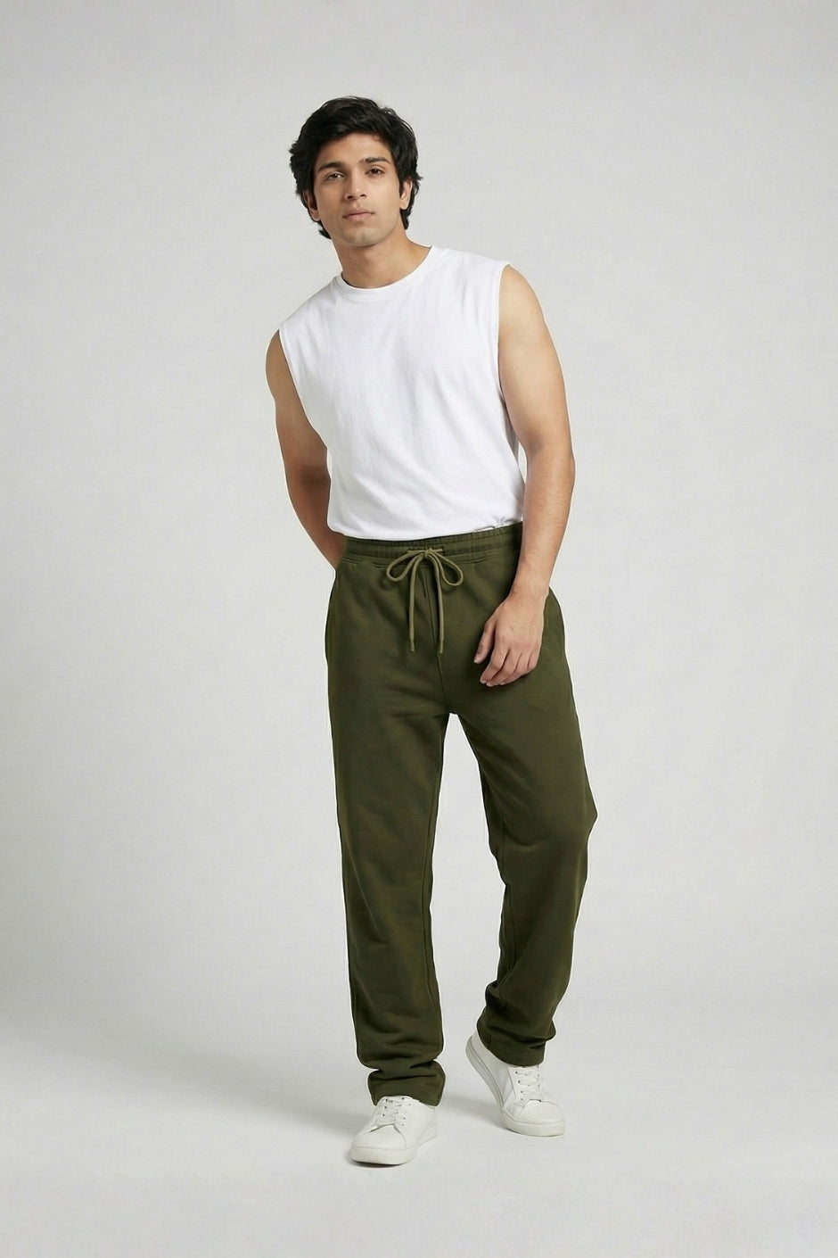 Man wearing a white sleeveless shirt and olive jogger on a plain background
