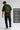 Person wearing a olive t-shirt with text and graphics, standing against a plain background.