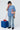 Person wearing a light blue t-shirt with a red and white design, holding a red phone, standing next to a blue cube on a white background.