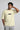 Man wearing a off white t-shirt with 'Be Kind' text on a plain background