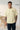 Man wearing a offwhite t-shirt with 'BORN TO RISE' text, standing indoors.