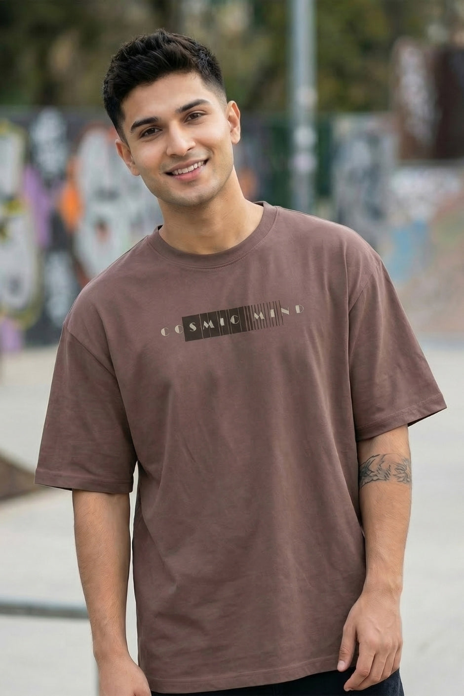 Man wearing a chocolate t-shirt with text, standing outdoors with graffiti in the background
