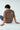 Person wearing a chocolate t-shirt with text and graphics on the back, sitting on a white floor.