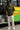 Man wearing a olive t-shirt with text and beige cargo pants standing in front of a colorful bus.