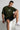 Man wearing a olive t-shirt with 'DIFFUSE' text, black shorts, and white sneakers on a light gray background.