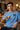 Man wearing a light blue t-shirt with 'FREE DOOM' text, holding a cup in a casual setting.