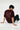 Person wearing a maroon red t-shirt with text on the back, sitting on a white floor.