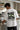 Person wearing a white t-shirt with a graphic design in a coffee shop setting