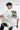 Person wearing a white t-shirt with text and graphics, sitting on a white chair against a white background.