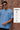 Man wearing a light blue t-shirt with text against a brick wall, featuring key highlights of the shirt.
