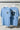 Two light blue t-shirts with 'North Edge' and '57' printed on them, hanging against a gray background.