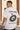 Person wearing a white t-shirt with a black graphic and text outdoors.
