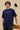 Man wearing a royal blue t-shirt with 'Outer Space' text, standing against a beige background.