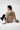 Person wearing a light beige t-shirt with text on the back, sitting on a white floor.