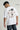 Person wearing a white t-shirt with text on the back, standing against a plain background.