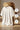 White t-shirt on a wooden chair with feature icons indicating wicking, hypoallergenic, and lightweight properties.