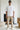 Man wearing a white t-shirt, beige cargo pants, and sunglasses indoors.