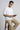 Man sitting on a stool holding a book against a plain background
