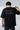 Person wearing a black t-shirt with text on the back against a white background