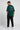 Person wearing a bottle green t-shirt with text on the back, standing against a white background