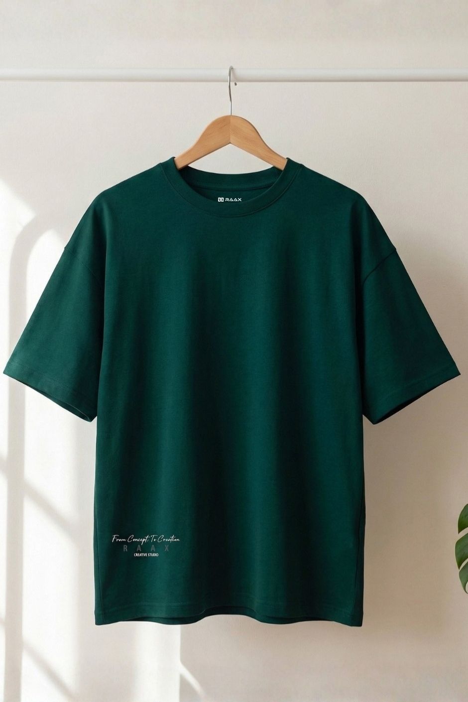 Bottle green t-shirt on a wooden hanger against a white wall