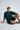 Person wearing a bottle green shirt and black shorts sitting on a white background