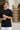 Man wearing a black t-shirt with product details on a blurred outdoor background