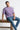 Man sitting on a wooden bench wearing a lilac t-shirt and blue jeans, with text annotations on the shirt.