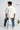 Person wearing an oversized white t-shirt with 'RAAX' branding, standing on a stool against a plain background.