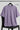 Lilac oversized t-shirt on a black chair with 'RAAX' branding.