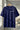 Royal blue t-shirt with 'REALM' logo on a hanger against a blurred indoor background