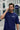 Man wearing a royal blue 'REALM' t-shirt, talking on a phone, with a blurred city street background.