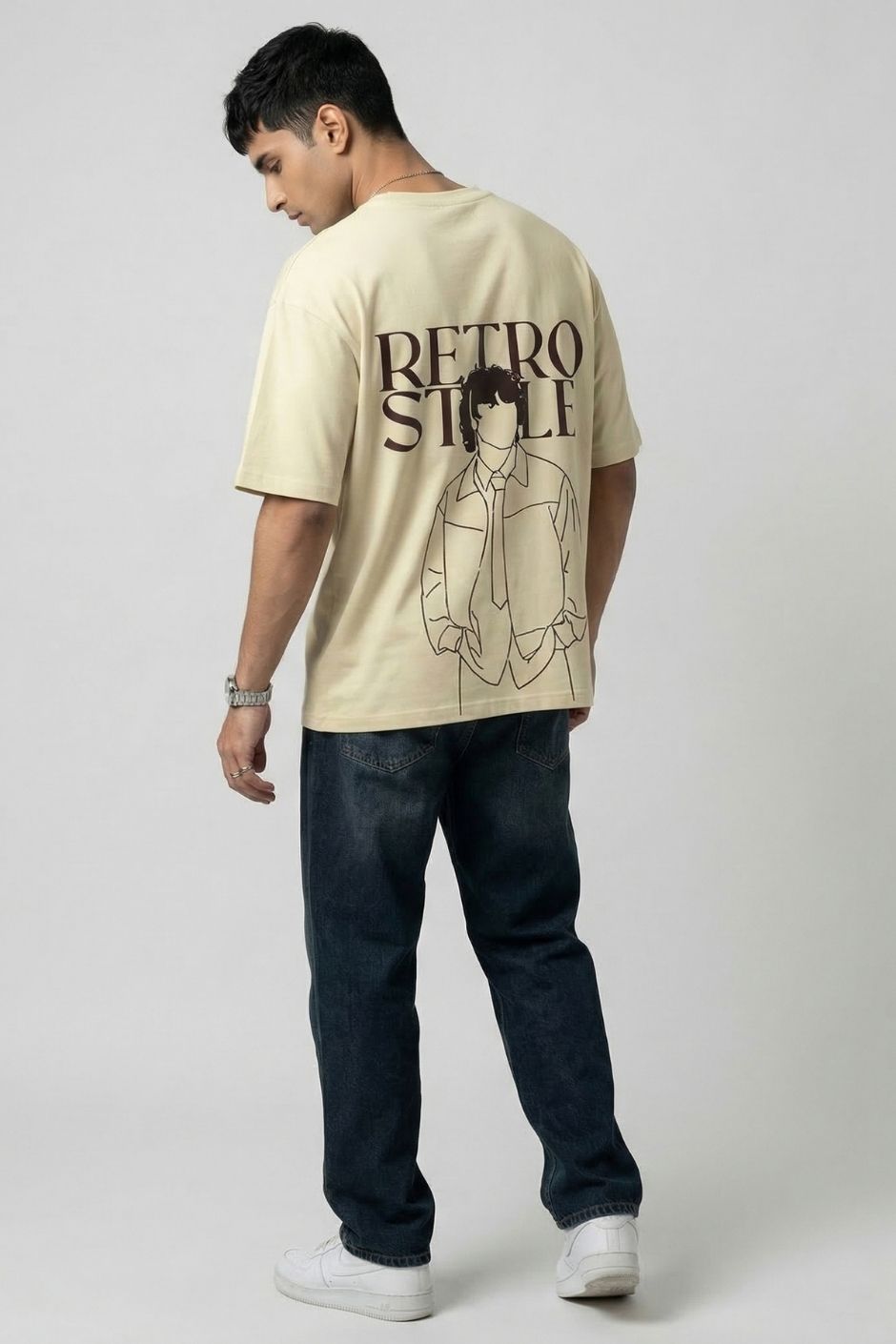 Person wearing a offwhite t-shirt with a graphic design on the back, standing against a plain background.