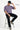 Man sitting on a stool wearing an oversized fit lilac t-shirt with 'Ruthless' text, black pants, and a black cap.