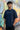 Man wearing a pastel blue t-shirt with text in front of a colorful graffiti wall.