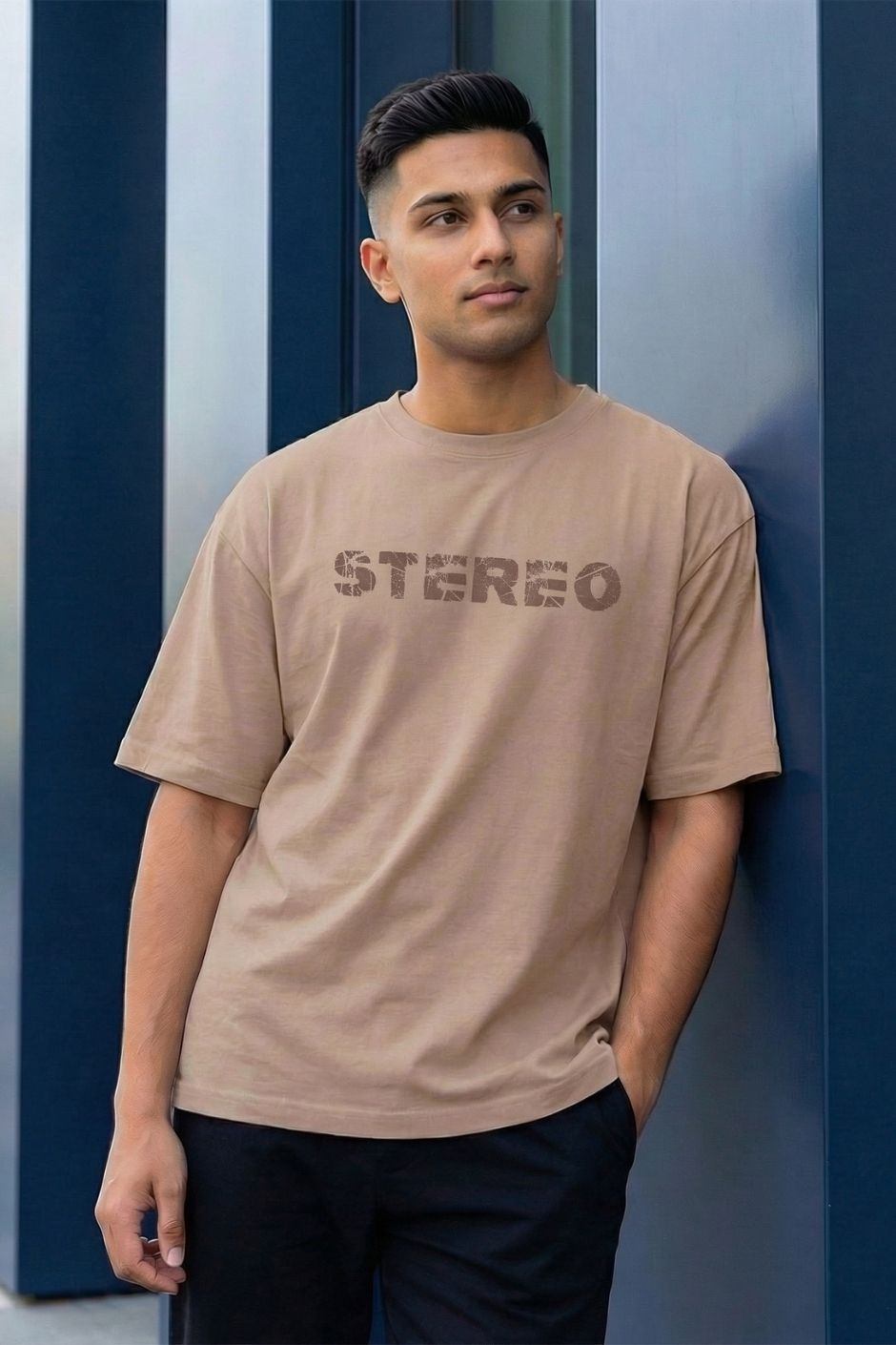 Man wearing a light beige t-shirt with 'STEREO' text against a blue wall.
