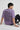 Person wearing a lilac t-shirt with text on the back, sitting on a light gray background