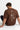 Person wearing a brown t-shirt with a compass design and text on the back, sitting on a white floor.