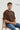 Man sitting on a chair wearing an oversized brown t-shirt with text.