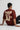 Person wearing a rust t-shirt with 'THIS IS NOT AI' text on the back, sitting against a white background.