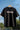 Black t-shirt with 'TOKYO NIGHTS' text on a hanger against a chain-link fence background