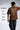 Man wearing a brown t-shirt with text and graphics, standing against a white background.