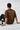 Person wearing a brown t-shirt with text and graphics, sitting on a white floor.