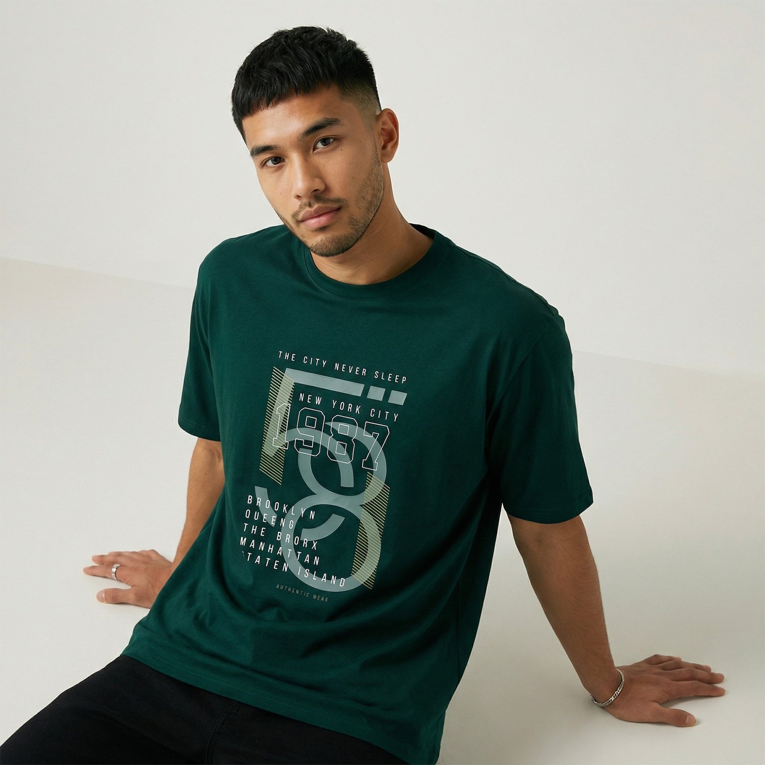 Man wearing a green t-shirt with a graphic design on a white background