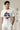 Man wearing a white t-shirt with text and graphics, standing against a plain background.