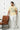 Man wearing a offwhite t-shirt with a graphic design, standing next to a brown leather chair.