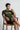 Man sitting on a wooden chair wearing a olive t-shirt with text design.